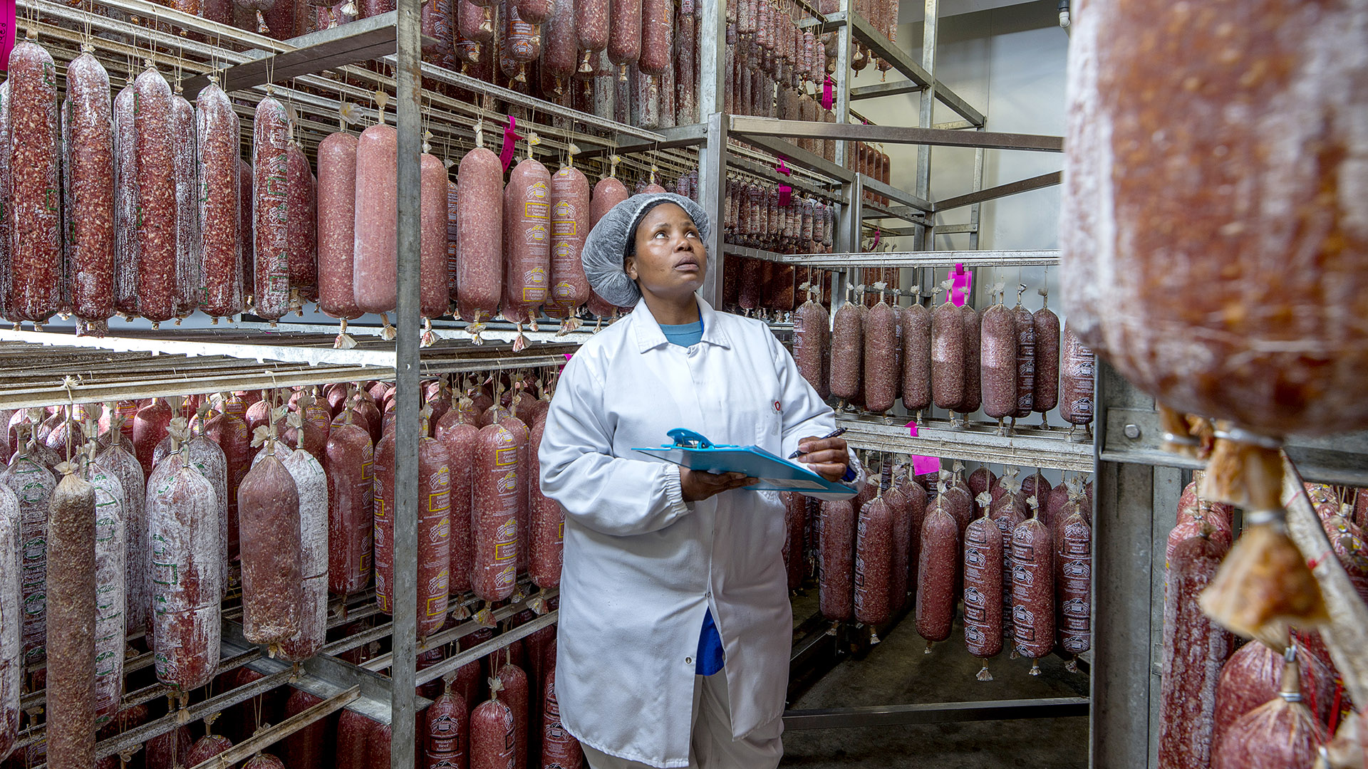 Staff member checking stock levels of cured salami