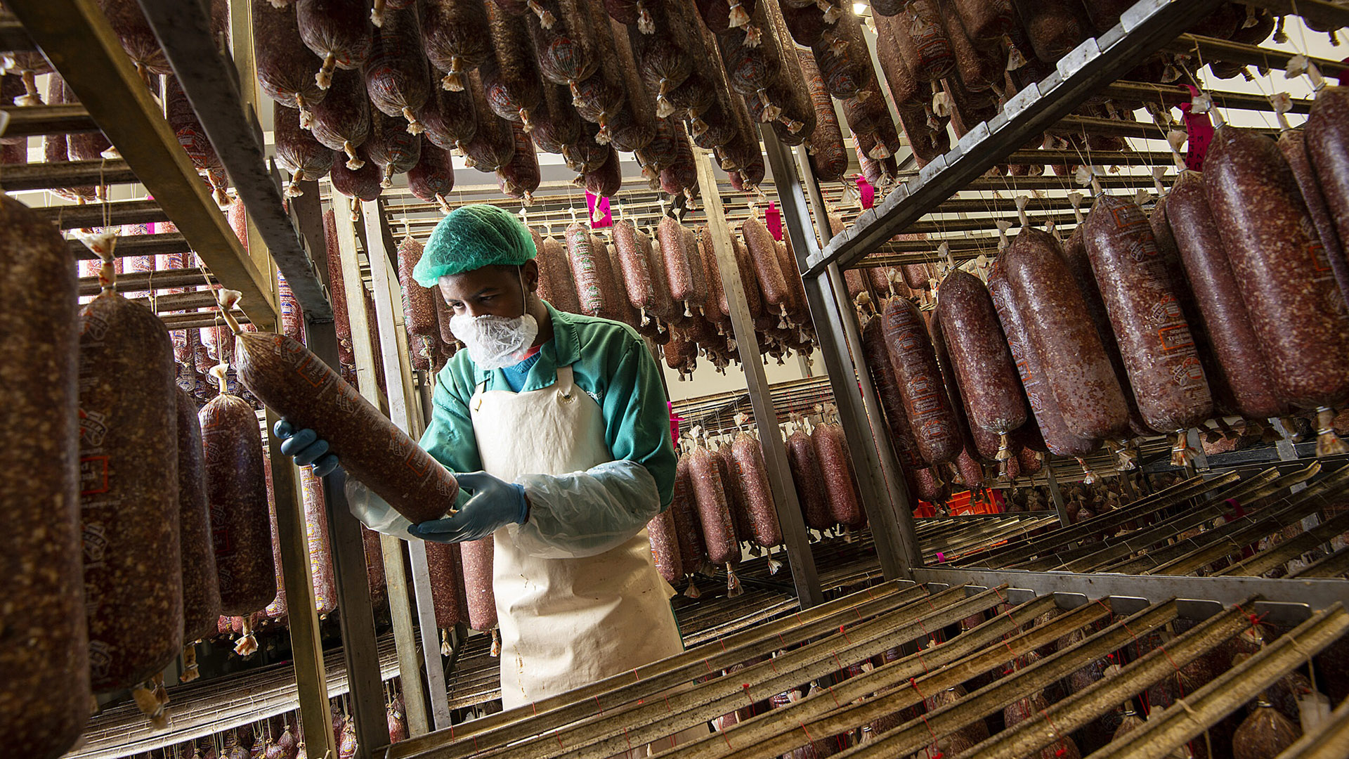 Quality controller inspecting hand-tied salami in the curing room